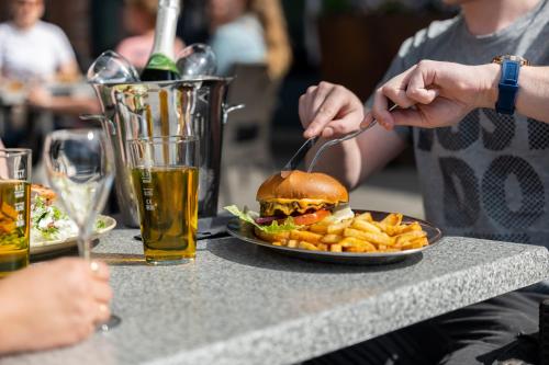 a person eating a hamburger and french fries on a table at Solo Sokos Hotel Torni Tampere in Tampere