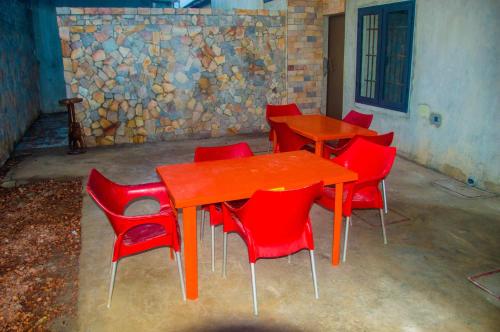 un grupo de sillas rojas alrededor de una mesa de madera en Chambre à proximité de l'aéroport., en Cotonou