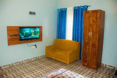 sala de estar con silla y TV en la pared en Chambre à proximité de l'aéroport., en Cotonou