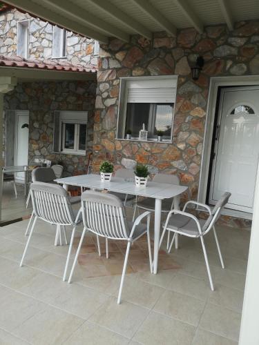 a table and chairs on a patio with a stone wall at Makis Nest Apart-Hotel in Vourvourou