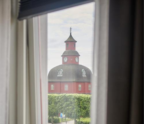 a view of a building with a clock tower from a window at Hotell Rådhuset in Lidköping