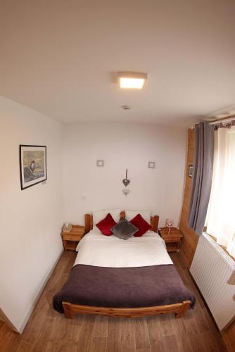 um quarto com uma grande cama branca com almofadas vermelhas em Le Chalet de la Source em Mouthe