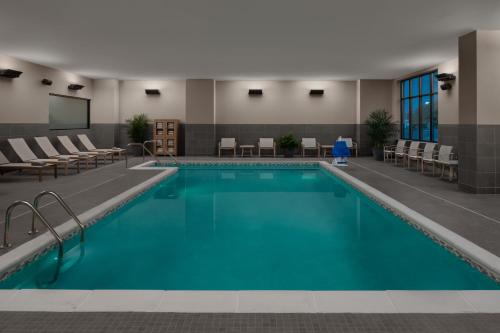 a pool in a hotel room with chairs and tables at Hyatt House Lansing-University Area in Lansing