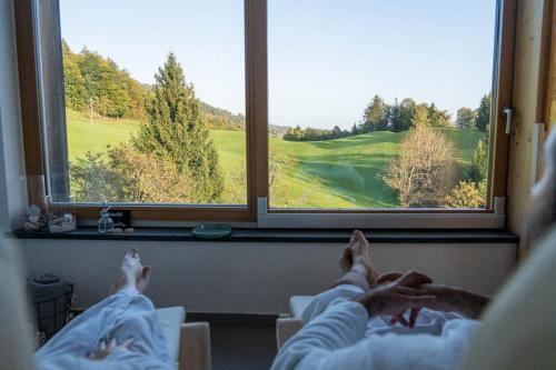 two people laying in beds looking out the window at a golf course at Na Kupčku Estate "Nature Reatreat & Wellness" in Idrija