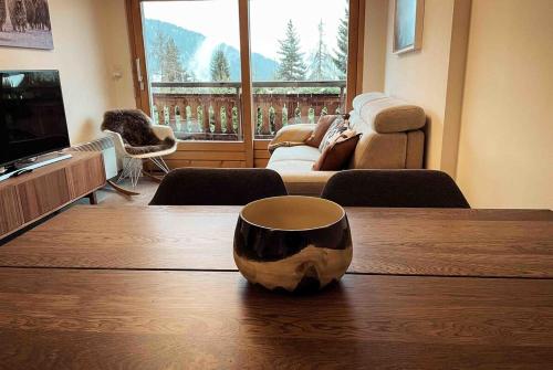 een woonkamer met een houten tafel met een kopje erop bij Quiet ski and golf apartment in Verbier