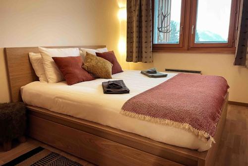 een slaapkamer met een groot bed met veel kussens bij Quiet ski and golf apartment in Verbier