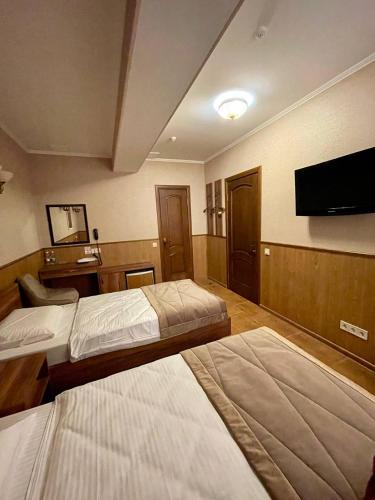 a hotel room with two beds and a flat screen tv at Sport Hotel 1 in Cherkasy