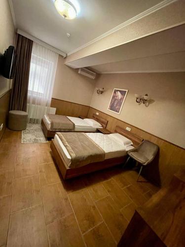 a bedroom with two beds and a chair in it at Sport Hotel 1 in Cherkasy