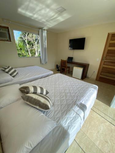 a large white bed in a bedroom with a television at Recanto Casa de Itaúna in Saquarema