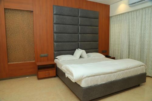 a bedroom with a large bed with a padded headboard at Hotel Sai D-lax in Shirdi