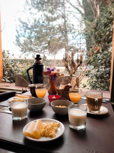 a table with plates of food and glasses of orange juice at La Saucina - Cabaña Rústica Chic in Tunuyán