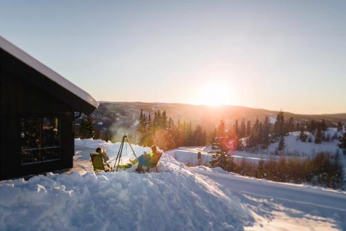 dos personas de pie en la nieve al lado de un edificio en Chill cabin - fantastic view and nice hiking area, en Aurdal