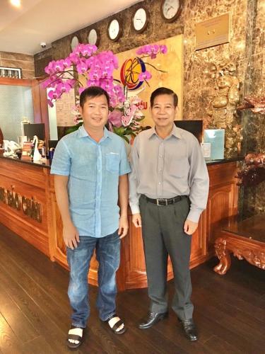two men standing in front of a counter with flowers at Long Bao Chau Hotel in Thu Dau Mot