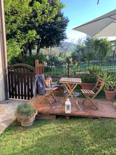a wooden deck with a table and chairs and an umbrella at Relais B&B Betty Bike in Sassofeltrio