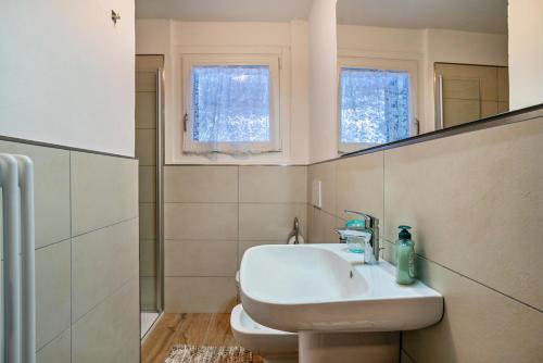 a white bathroom with a sink and a mirror at Appartamento Polsa 4 in Brentonico