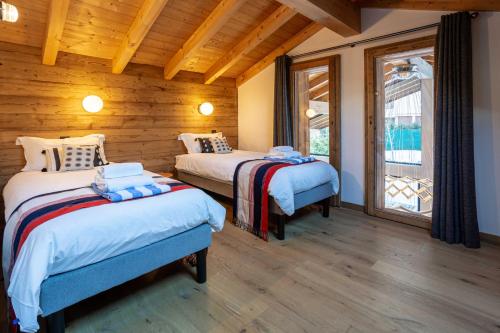 deux lits dans une chambre aux murs en bois dans l'établissement Chalet Gloribel, à Chamonix-Mont-Blanc