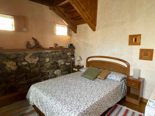 een slaapkamer met een bed en een stenen muur bij Moradas Busdongo 