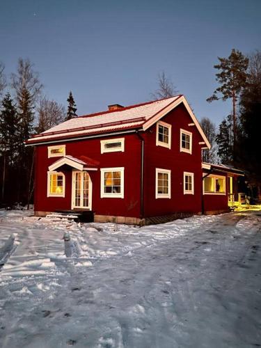 une maison rouge avec de la neige devant elle dans l'établissement Lyxig oas med modern elegans, à Mora