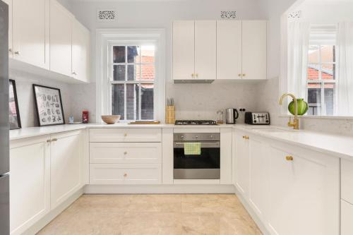 a white kitchen with white cabinets and an oven at Stunning Terraced Apartment near the Sydney Opera House in Sydney