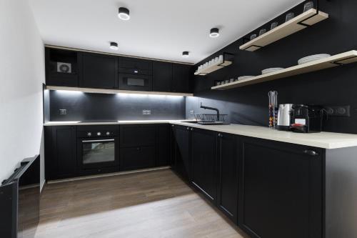 une cuisine avec des armoires noires et des comptoirs blancs dans l'établissement Appartement Design en Duplex 2BR à Oberkampf, à Paris