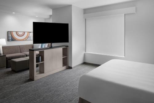 une chambre d'hôtel avec une télévision et un canapé dans l'établissement Hyatt House Lansing-University Area, à Lansing