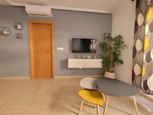 Cette chambre dispose d'une table, de deux chaises et d'une télévision. dans l'établissement Elegante piso con terraza, garaje, piscina y AC, à El Campello