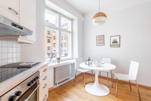 Cozy, spacious and calm city home - top location في هلسنكي: مطبخ أبيض مع طاولة بيضاء وكراسي