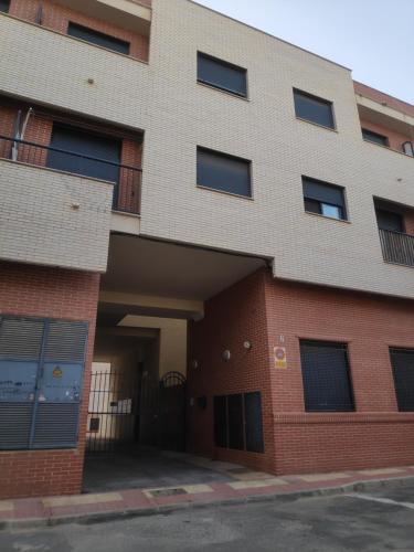 un grand bâtiment en briques avec un parking dans l'établissement Elegante piso con terraza, garaje, piscina y AC, à El Campello