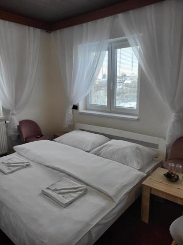 Schlafzimmer mit einem großen weißen Bett und einem Fenster in der Unterkunft Hotel Styl Hlinsko in Hlinsko