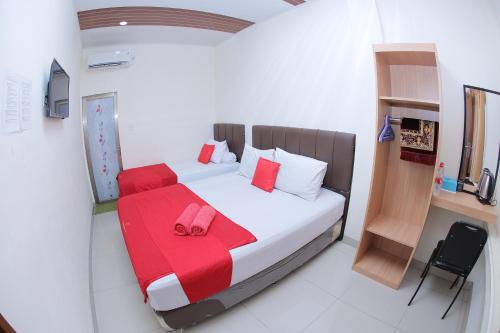- une chambre avec un lit et une couverture rouge dans l'établissement grand koetaradja permai hotel, à Luengbata