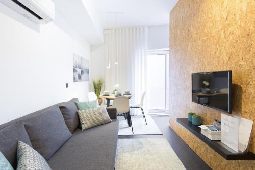 a living room with a couch and a tv on a wall at QP Trindade Apartments in Porto