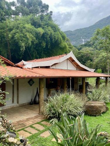Casa Portal Sagrado Matutu- Aiuruoca MG في أيوريوكا: منزل بسقف احمر على ارض خضراء