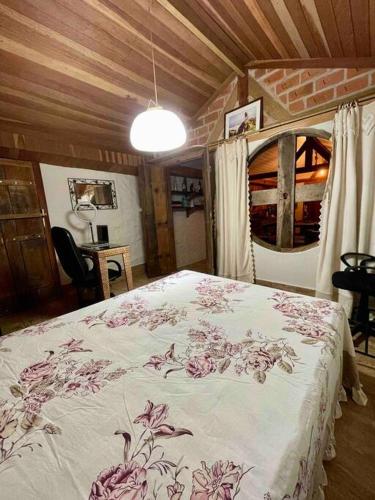1 dormitorio con 1 cama con colcha de flores en Casa Portal Sagrado Matutu- Aiuruoca MG en Aiuruoca