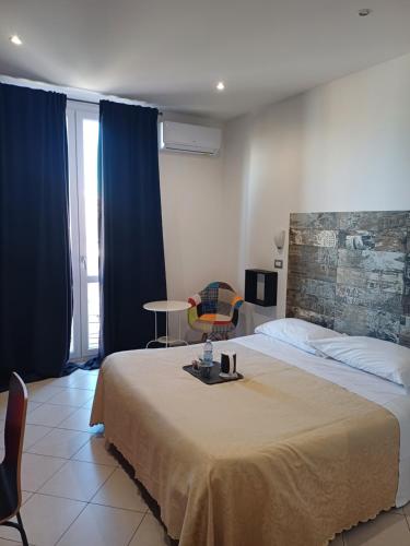 sypialnia z dużym łóżkiem z niebieskimi zasłonami i stołem w obiekcie Hotel Centrale w Syrakuzach