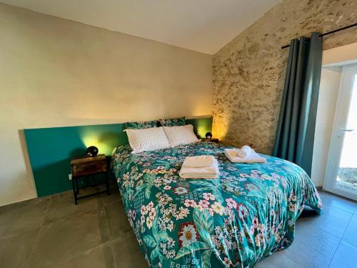 une chambre avec un lit avec un couvre-lit fleuri dans l'établissement La Parenthèse du Var - Gîte avec grande terrasse vue sur piscine, à Saint Antonin du Var