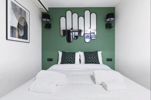 une chambre avec un lit blanc et un mur vert dans l'établissement HSH Parmentier-Couronnes II Appartement Design 4P-1BR, à Paris