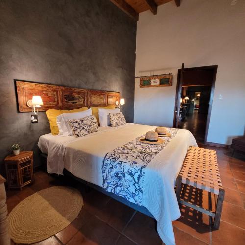 a bedroom with a large white bed with a bench at Finca La Saucina Casa de Campo in Tunuyán