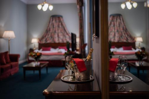 una camera d'albergo con due letti e un tavolo con bicchieri da vino di Hotel Liberty a Praga