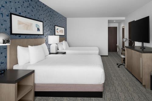 a hotel room with two beds and a flat screen tv at Hyatt House Lansing-University Area in Lansing