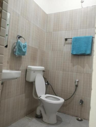 a bathroom with a toilet and a sink and a blue towel at Hotel Relex in New Delhi