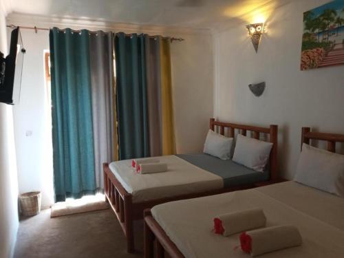 a bedroom with two beds and a window at Jambo Kendwa Villa in Kendwa