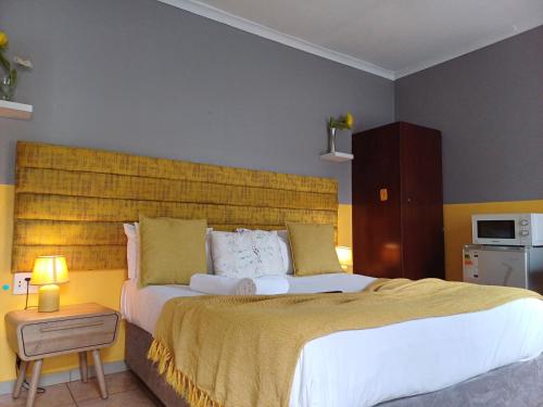 a bedroom with a large bed with a yellow headboard at Horizon Bed and Breakfast in Roodepoort