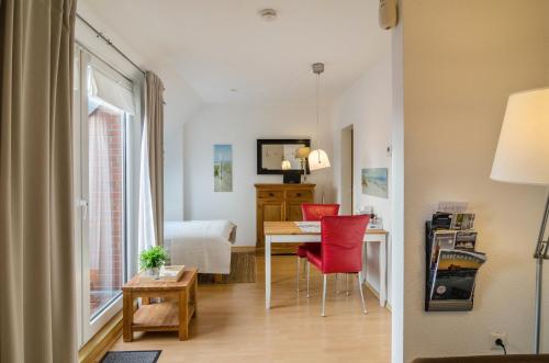 Habitación con escritorio y mesa con sillas rojas. en Windrose, en Wilhelmshaven