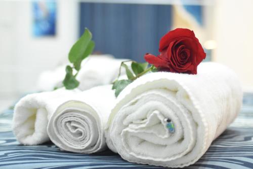 una rosa sentada encima de las toallas en una cama en Cico Art Suite, en Nápoles