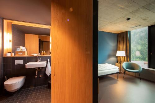 een badkamer met een wastafel, een toilet en een bed bij 54 Hochgenuss in Schattdorf
