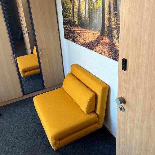 a yellow chair in a train with a picture on the wall at Zimmer8 bei Göcke in Recke