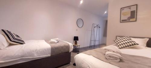 a bedroom with two beds and a clock on the wall at 301 Grosvenor House-City Centre in Wakefield