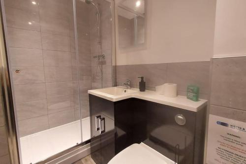 a bathroom with a toilet and a sink and a shower at 301 Grosvenor House-City Centre in Wakefield