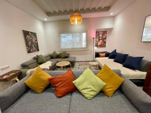 a living room with a couch with colorful pillows at Au Cœur Des Sables D’or - Harhoura in Temara