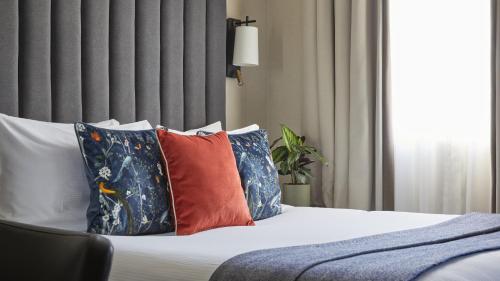 a bedroom with a bed with colorful pillows at The Selwyn, Richmond in Richmond upon Thames